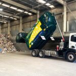 NAWMA kerbside collection truck reversed into MRF with hopper lifted to tip recycling contents out onto floor
